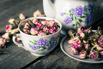 Vintage teapot and cup with blooming tea flowers on wooden background