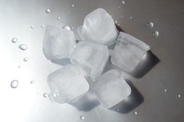 ice cube on silver background with water drops