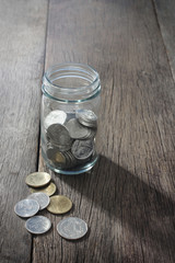 Baht Thailand coins, glass bottles and coins placed on a wooden table.