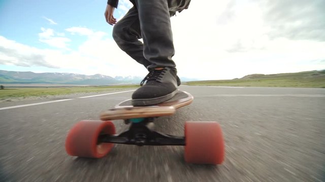 Guy on his longboard skate. Close up of longboard and foot. Side view. Tracking shot