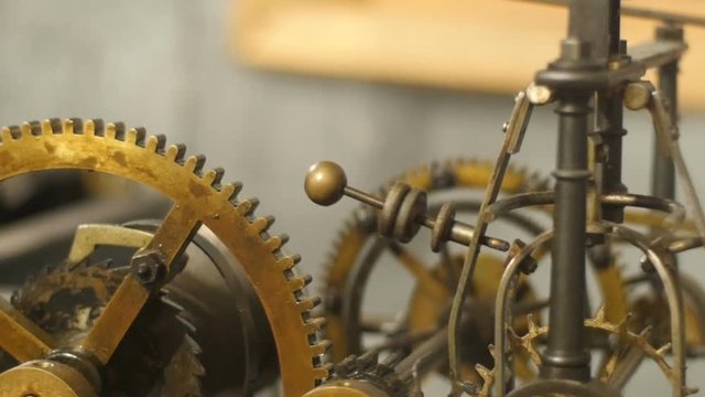 Close up detail view of complicated bronze internal clock mechanism with gearwheels and links