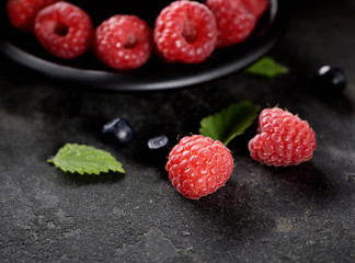 raspberries and blueberries in a bowl on a dark background
