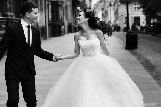 Wind blows bride's dark hair while groom holds her hand
