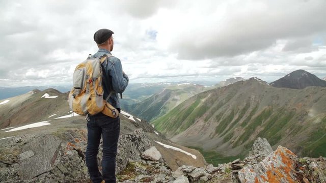 Guy with a travel backpack on the top of a boulder
