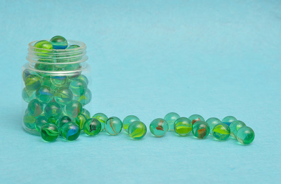 A Collection Of Marbles In A Plastic Jar Displayed On A Blue Background