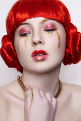 Woman in red and gold fashion make up and red hair on white background in studio photo. Art beauty photo