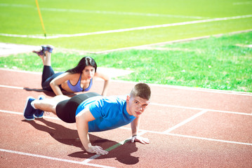 Fototapeta premium Young couple doing push ups on track.