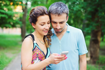 Obraz premium Beautiful happy couple together on a walk with their smart phones 