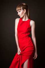 beautiful woman model posing in simple elegant red dress in the studio on black background