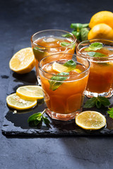 iced tea with mint and lemon in glasses on dark background