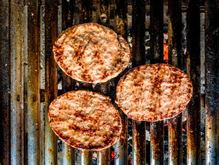 Grilling burgers on barbecue BBQ grill on hot charcoal.