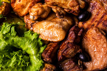 Grilled chicken wings and legs with lettuce and black olives