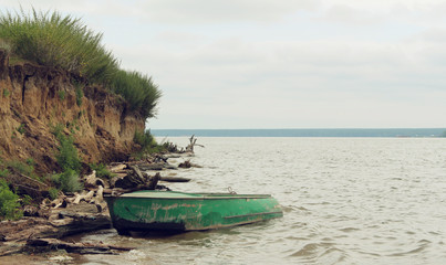 Fototapeta na wymiar Old green boat with oars on the coast