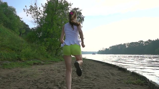 Slender brunnete girl running on sandy summer riverside. Super slow motion crane video