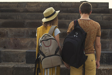 Concept traveling together, honeymoon, wanderlust. Stylish couple in love with backpacks on shoulders. Back view.