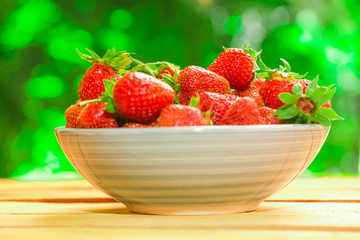 fresh strawberries in a blue plate on blurred background