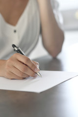 Closeup of woman's hand writing on paper with pen