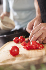 Männerhände beim Tomatenschneiden