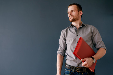 Bearded businessman with red folder looking away