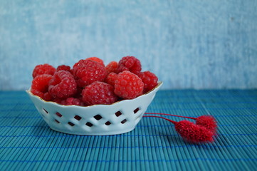 Fresh juicy raspberries in a porcelain dish. Selective focus
