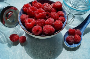 Fresh juicy raspberries in a porcelain dish. Selective focus
