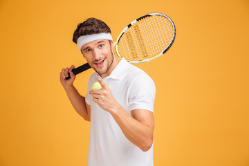 Happy man tennis player holding racket and pointing on you