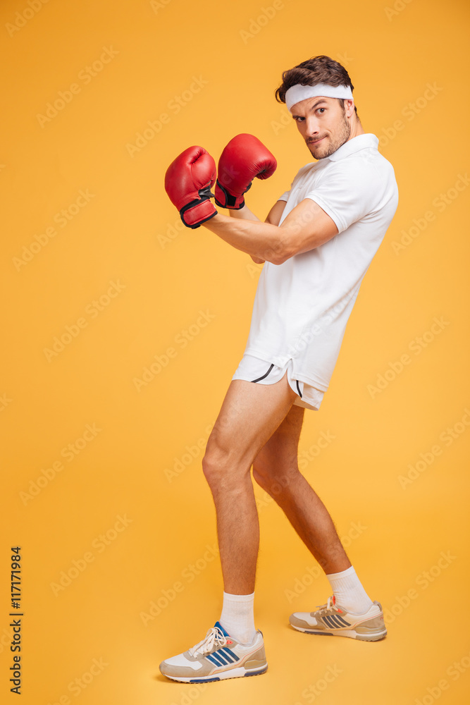 Poster Strong young man boxer in red gloves standing and posing