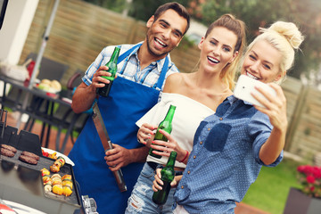Group of friends having barbecue party and taking selfie