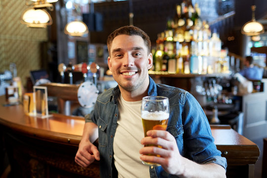 happy man drinking draft beer at bar or pub