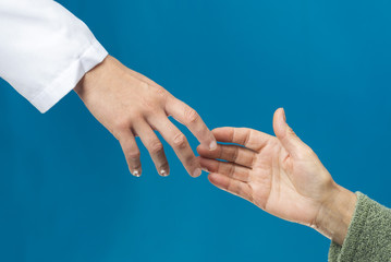 Old and young holding hands on light blue background, closeup