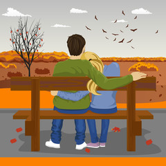 Back view of young couple sitting together on bench outdoors in autumn