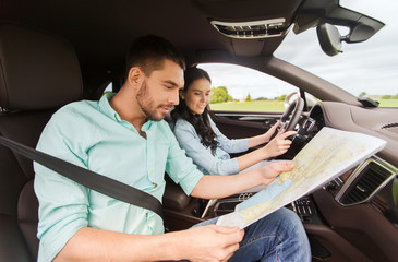 happy man and woman with road map driving in car