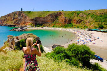 Blonde woman taking pictures at Bolata bay, Bulgaria, Black Sea.