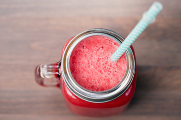 Watermelon smoothie in a mason jar on wooden background. Selective focus
