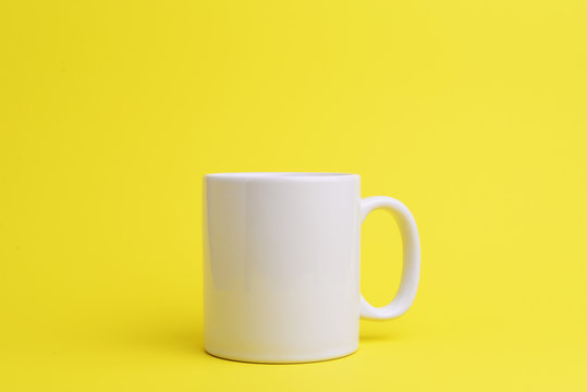 White coffee cup on yellow background.