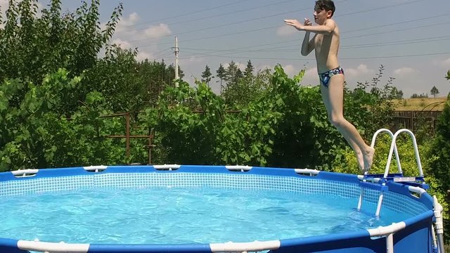 Swimming pool. Young boy jumping into the water in pool. Slow motion. HD
