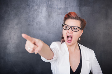 Angry screaming teacher pointing out on blackboard background