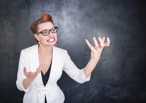 Angry teacher in glasses on blackboard background