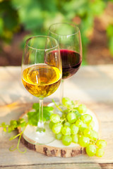 Green grapes and two glasses of the white and red wine on the vi