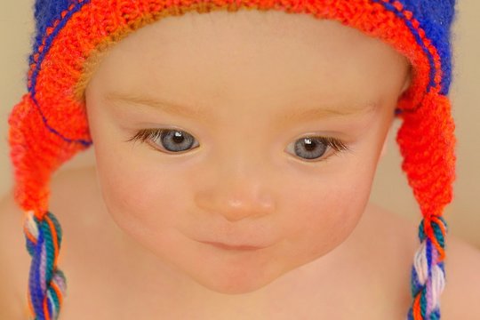 Cute baby with expressive eyes in knitted hat which his grandmother made.
