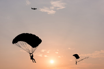 Silhouette von Fallschirm und Flugzeug auf Sonnenuntergang Hintergrund