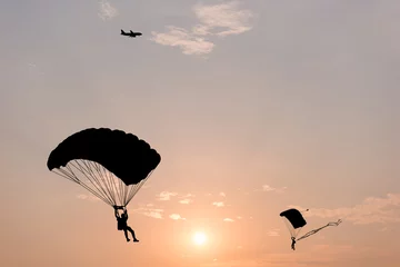 Foto auf Acrylglas Luftsport Silhouette von Fallschirm und Flugzeug auf Sonnenuntergang Hintergrund