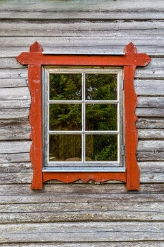 One window with red frames on log house wall, traditional style. 