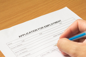 Filling for application for employment form on wooden table