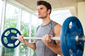 Fototapeta na wymiar Fitness man lifting barbell in gym