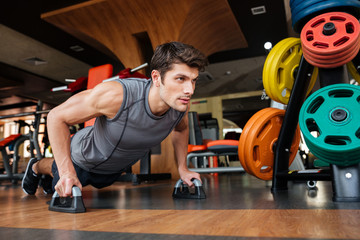 Fitness man working out and doing push-ups in gym
