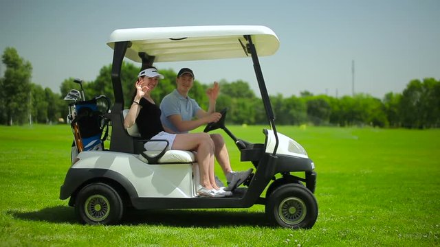 Young couple sitting in the cart at the course