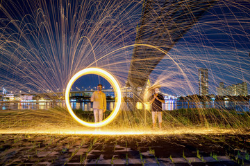 Hot Golden Sparks Flying from Man Spinning Burning Steel Wool under Bhumibol Bridge in Bangkok Thailand., Long Exposure Photography using Steel Wool Burning.