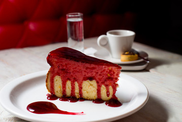 slice of cake on a white plate and cup of coffe on the background