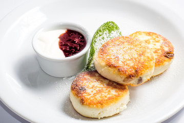 cottage cheese pancakes with jam and cream on a white plate